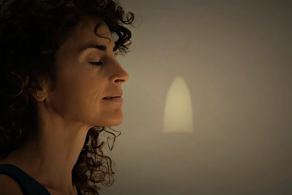 Ana de perfil con los ojos cerrados, a la luz de una vela
